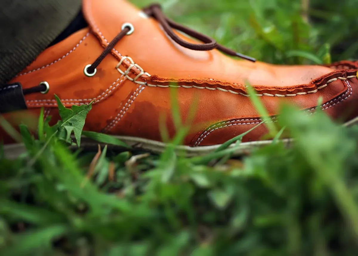 Stylowy sneaker na drewnianym podłożu obok miarki krawieckiej, ilustrujący sposób mierzenia długości wkładki buta.